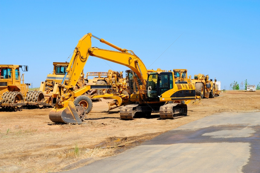 桶重型建筑設備停在一條新的瀝青路挖土機和重型設備沿線閑置的干上沿著建造